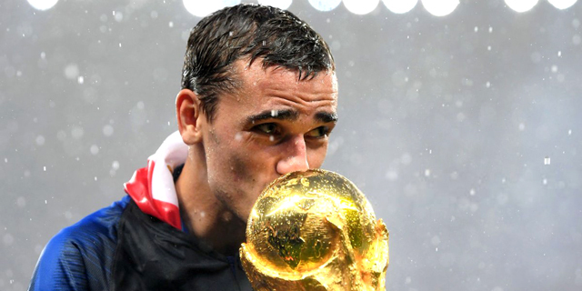 אנטואן גריזמן חלוץ נבחרת צרפת מנשק את הגביע העולמי