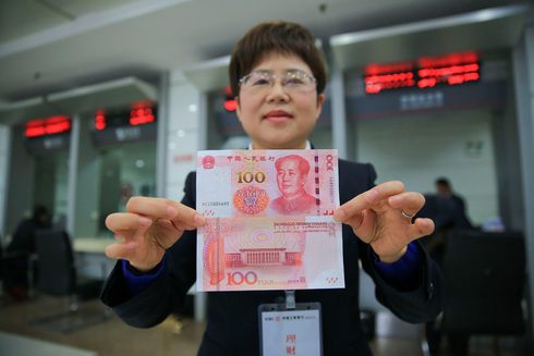בנקאית סינית מחזיקה בשטר של 100 יואן, צילום: גטי אימג