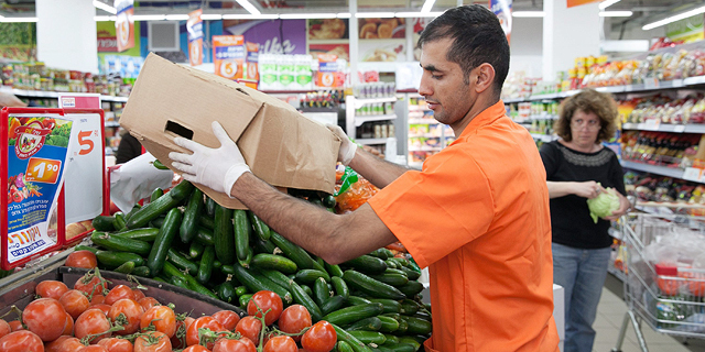 עובד ממלא את מגשי ה ירקות ב סופרמרקט