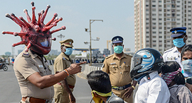 שוטר ב הודו עם קסדת וירוס קוביד 19 מתריע אזרחים להיכנס לבידוד פנאי