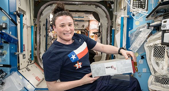 אסטרונאוטית מחזיקה את הקופסה של ספייס פארמה בתחנת החלל הבינלאומית