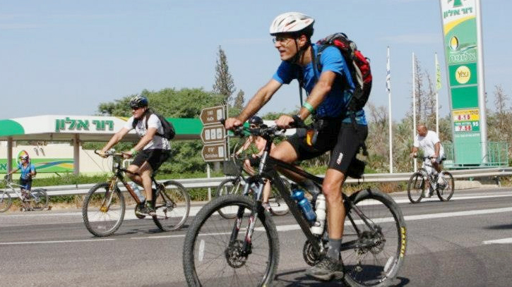 רוכבי אופניים על רקע תחנת דלק דור אלון פנאי