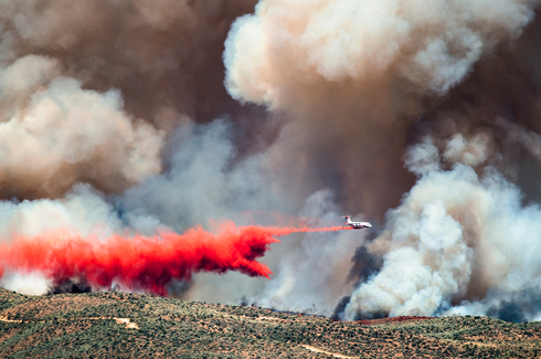 מטוס כיבוי מוסב על רקע שריפת ענק, צילום: שאטרסטוק