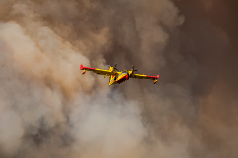 מטוס כיבוי ייעודי CL515 יוצא מענן עשן, צילום: שאטרסטוק