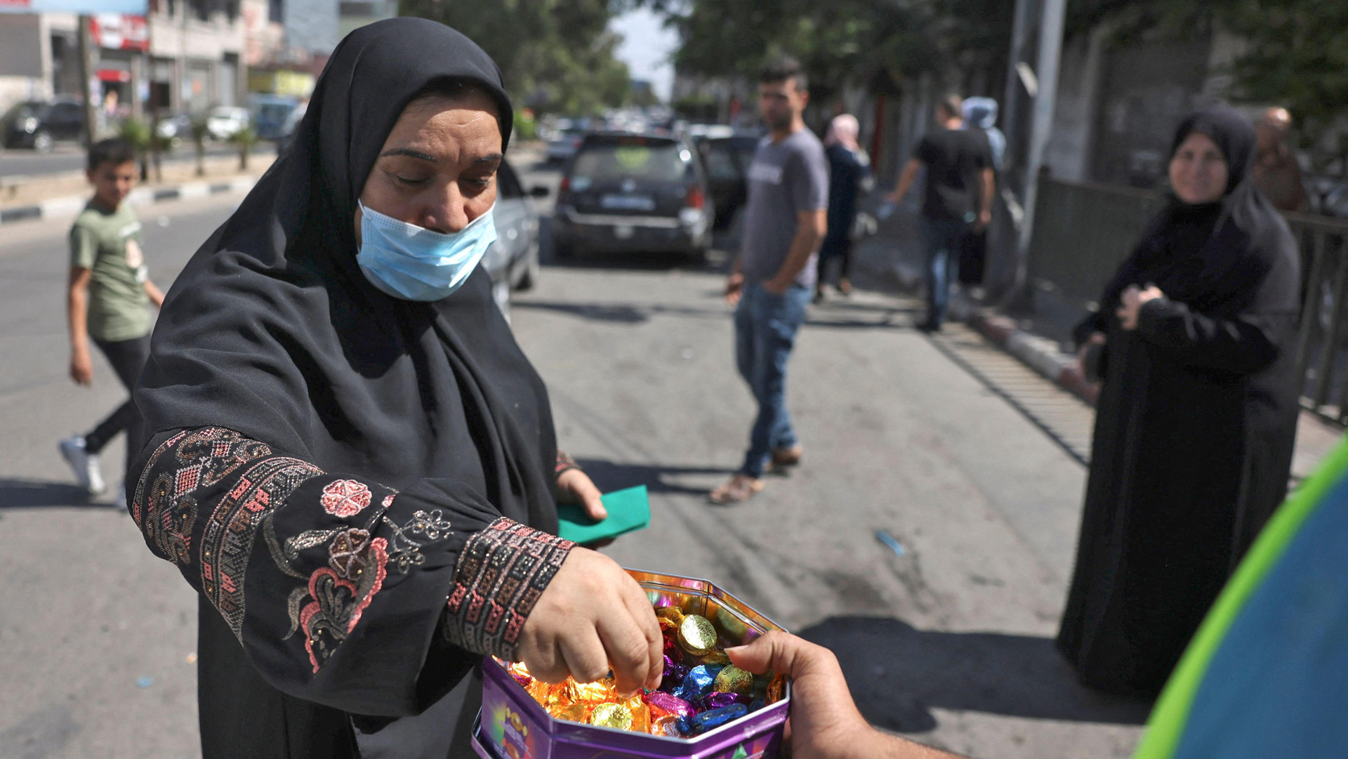אשה מקבלת ממתקים שמחולקים ברחוב ב רצועת עזה