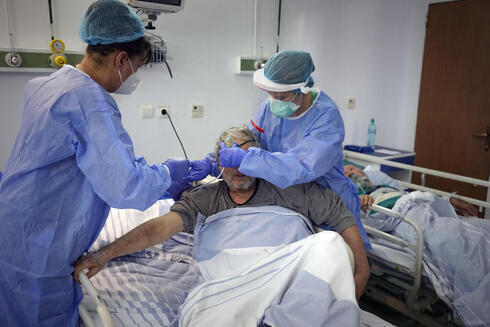 "הגבלות - עד שאנשים ישכנעו עצמם להתחסן". מטפלים בחולה קורונה בבוקרשט, צילום: איי פי