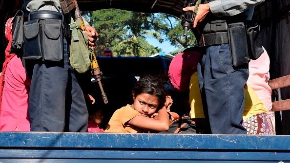 שוטר במיאנמר מלווה ילדה בת רוהינגה למחנה שלה לאחר שניסתה לברוח מהמדינה, צילום: גטי