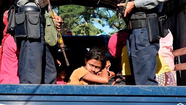 שוטר ב מיאנמר מלווה ילדה בת רוהינגה למחנה שלה לאחר שניסתה לברוח מהמדינה