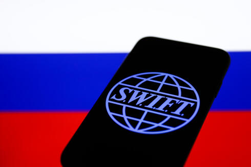 הלוגו של SWIFT על רקע דגל רוסיה, רויטרס