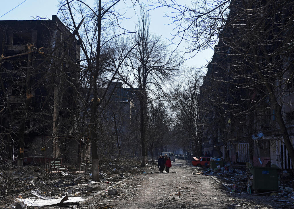 אזרחים אוקראינים הולכים בין ההריסות ב מריופול אוקראינה