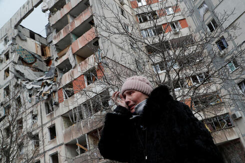 אישה על רקע בניינים הרוסים במריופול, רויטרס