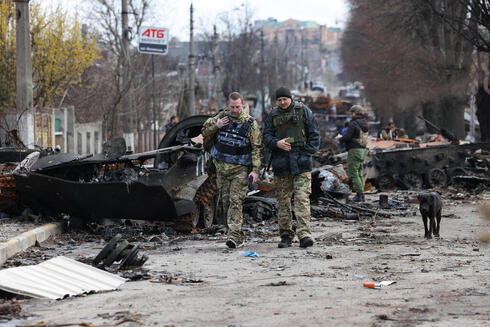חיילים אוקראינים מפטרלים סביב הרכבים השרופים בבוצ