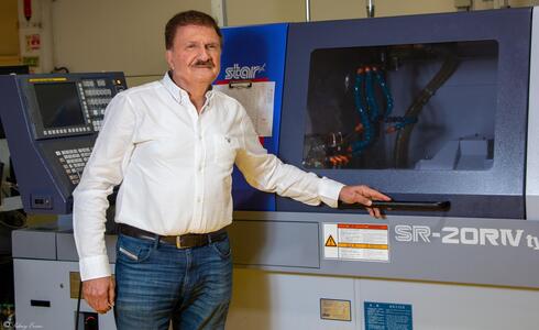 Dr Emil Somekh in front of a STAR Swiss-type CNC, used to manufacture small medical parts 