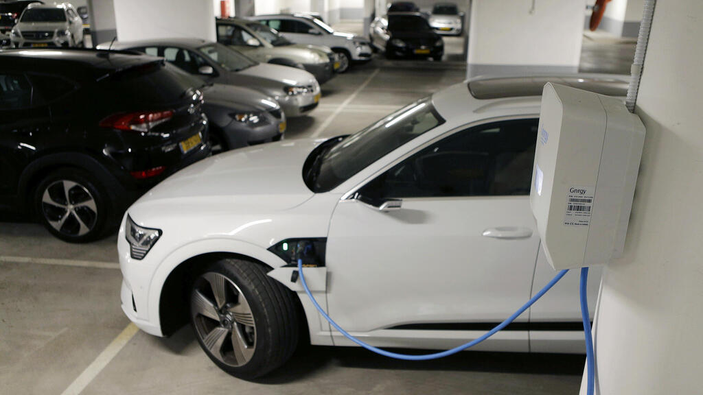 רכב אאודי לבן חשמלי בטעינה בחניון (צילום: עמית שעל) רכב אאודי לבן חשמלי ב טעינה ב חניון בניין משותף מכונית חשמלית