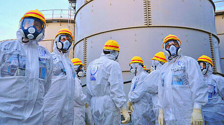 עובדים לבושים בחליפות נגד קרינה רדיואקטיבית לאחר האסון ב פוקושימה יפן מרץ 2011