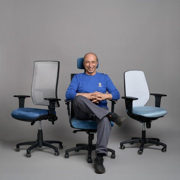 מתוך פרויקט הצילום "עובדים ומוצרים". בתמונה – ארתור, מנהל מחלקת המרפדייה, עם שלושה דגמים של כסאות מחשב המיוצרים במפעלי חברת 2sit, יונתן בלום