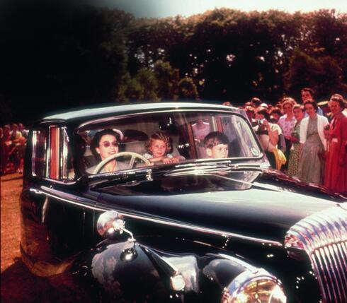 המלכה אליזבת נוסעת ברכב הדיאמלר המשפחתי בשנת 1957 סביב טירת ווינדזור עם הנסיך (כעת המלך) צ