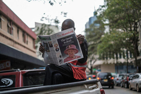 אדם קורא עיתון בניירובי, קניה, המבשר על מותה של המלכה אליזבת, AFP