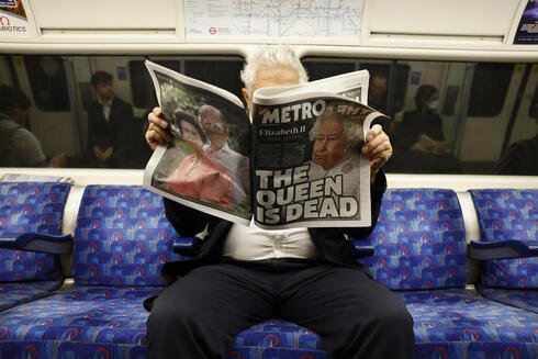 "המלכה מתה". נוסע ברכבת בלונדון מעיין בעיתון "מטרו", EPA