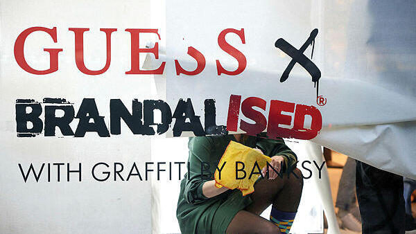 עובדי חנות גס בלונדון מכסים את חלון הראווה שבו הוצג גרפיטי של בנקסי. אמן הגרפיטי מאשים את החברה בשימוש ביצירות אמנות שלו ללא אישור