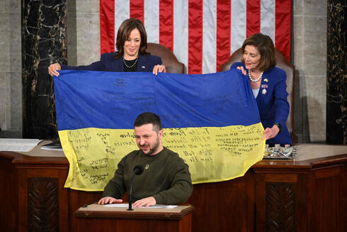 זלנסקי נואם בקונגרס, כשמאחוריו מניפות יו"ר בית הנבחרים ננסי פלוסי וסגנית הנשיא קמלה האריס דגל שהעניק להן, עם חתימות של לוחמים אוקראינים בחזית, צילום:AFP