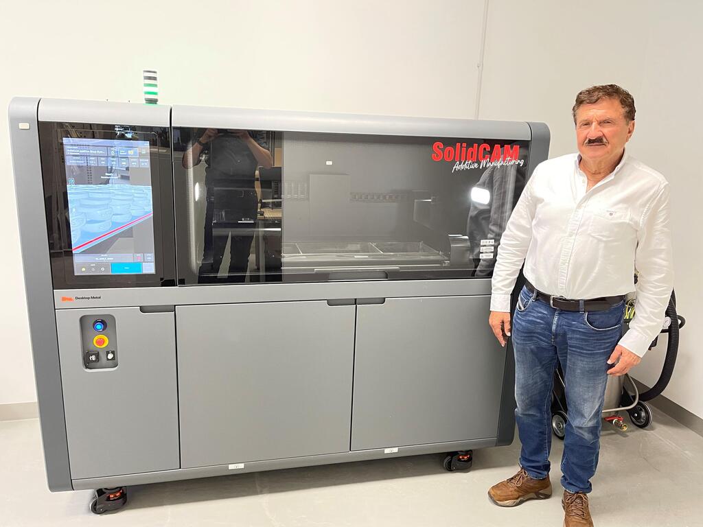 Dr. Emil Somekh stands next to a Desktop Metal Shop system, at the SolidCAM technology center in Germany 