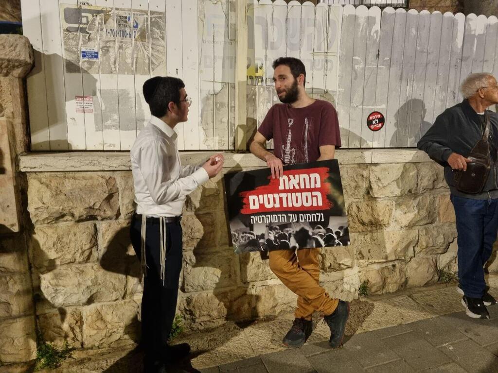 מפגין וצעיר חרדי משוחחים ליד בית ראש הממשלה בירושלים