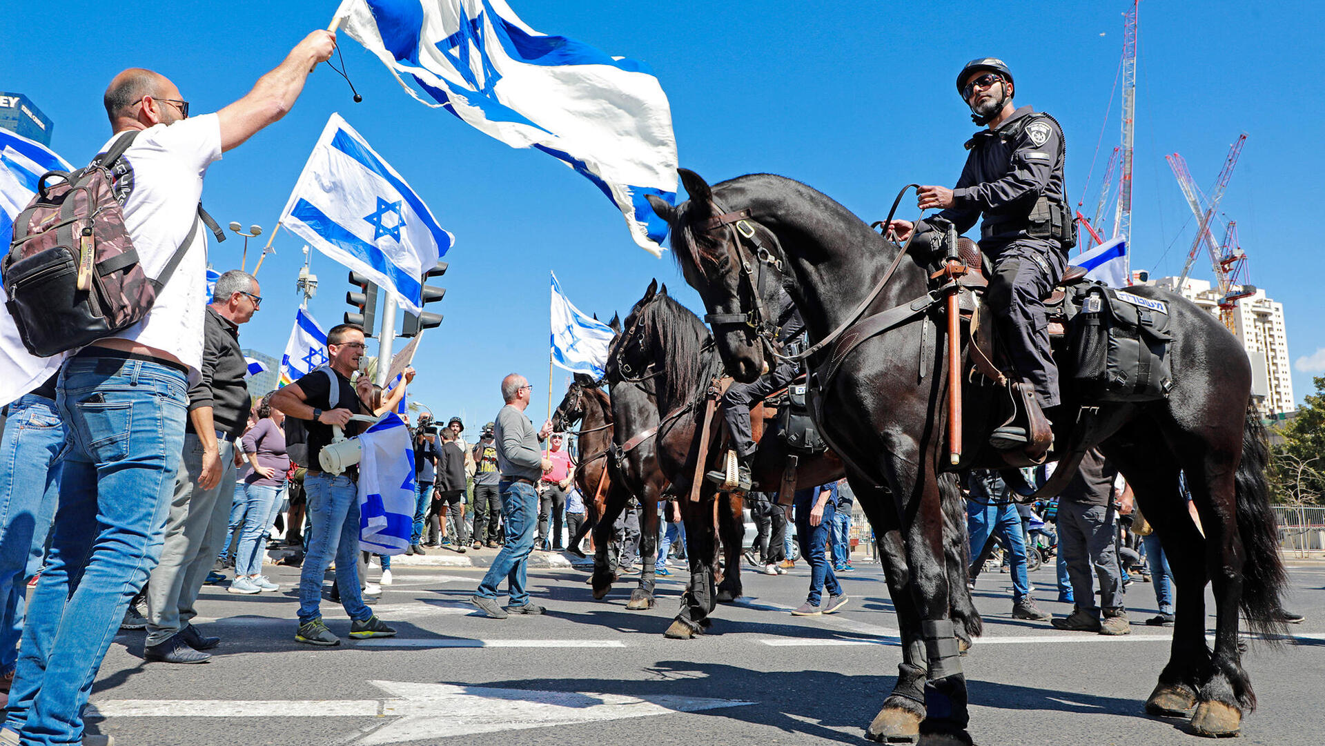 כוח משטרה רכוב שוטרים על סוסים מול מפגינים