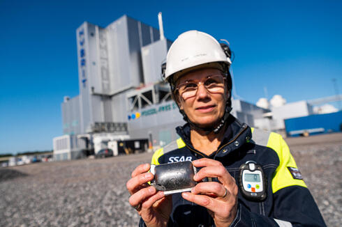 עובדת של יצרנית הפלדה השוודית SSAB מציגה גוש של ברזל גולמי שהופק ללא פליטת מזהמים. הליוס הישראלית היא אחת המתחרות המבטיחות בתחום, צילום: Jonathan NACKSTRAND / AFP
