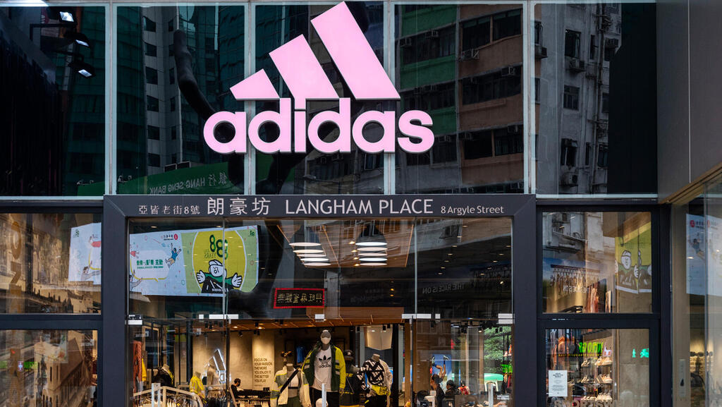 הולכי רגל חולפים על פני החנות והלוגו של מותג בגדי הספורט הרב-לאומי הגרמני אדידס בהונג קונג.