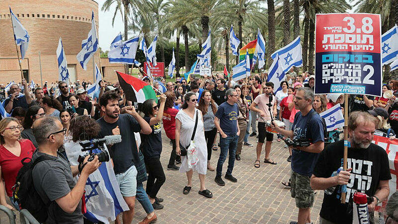 מפגינים עם שלטי מחאה ו דגלי ישראל ו אשף דגלי פלסטין מוחים ב אוניברסיטת תל אביב