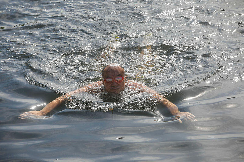 אדם שוחה בנהר ליאנגמה ב בייג'ינג סין ברקע גל החום יולי 2023 משבר האקלים