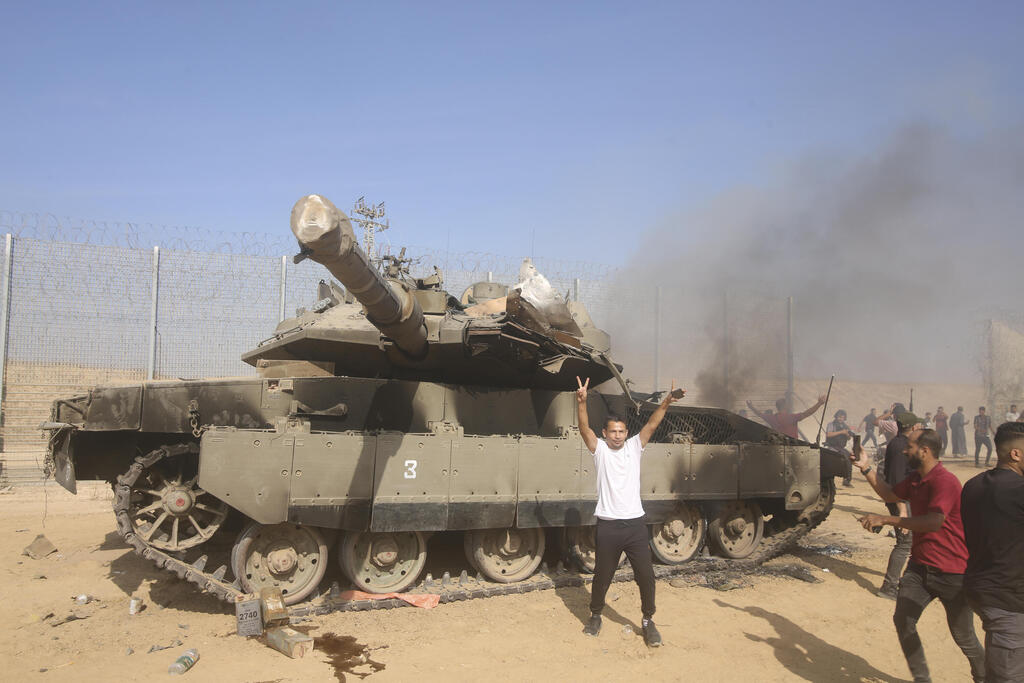 פלסטינים חוגגים לצד טנק ישראלי שרוף ב גבול עזה 7.10.23