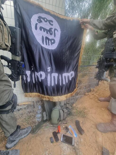 IDF soldiers holding up an ISIS flag left by Hamas terrorists. 