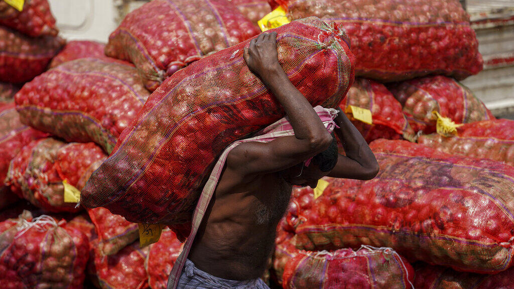 אדם סוחב שק בצל בשוק בהיידרבאד, הודו