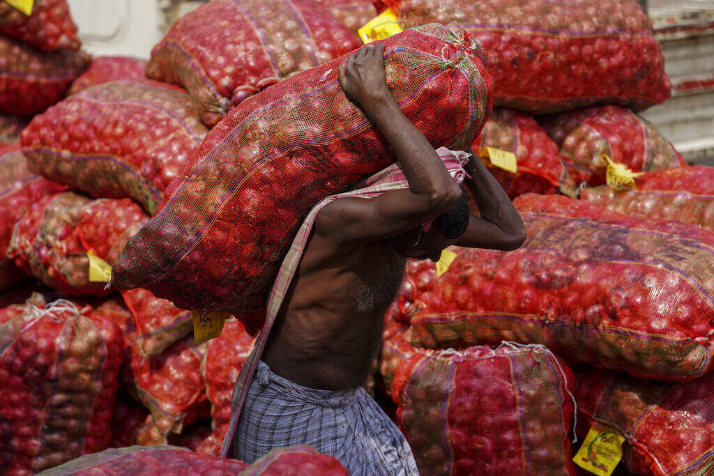 אדם סוחב שק בצל בשוק בהיידרבאד, הודו