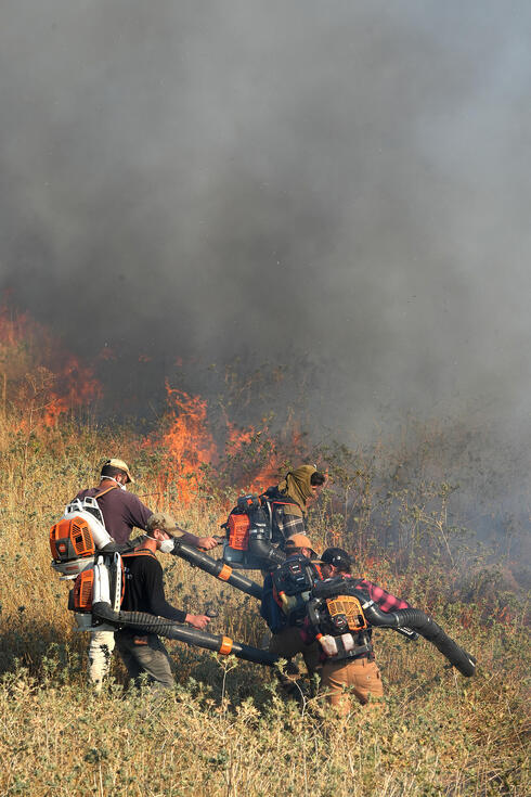 אזרחים מסייעים בכיבוי אש אחרי מתקפה בצפון. חזבאללה הוכיח את יכולותיו לאיים על מטרות בעומק ישראל , צילום: אפי שריר