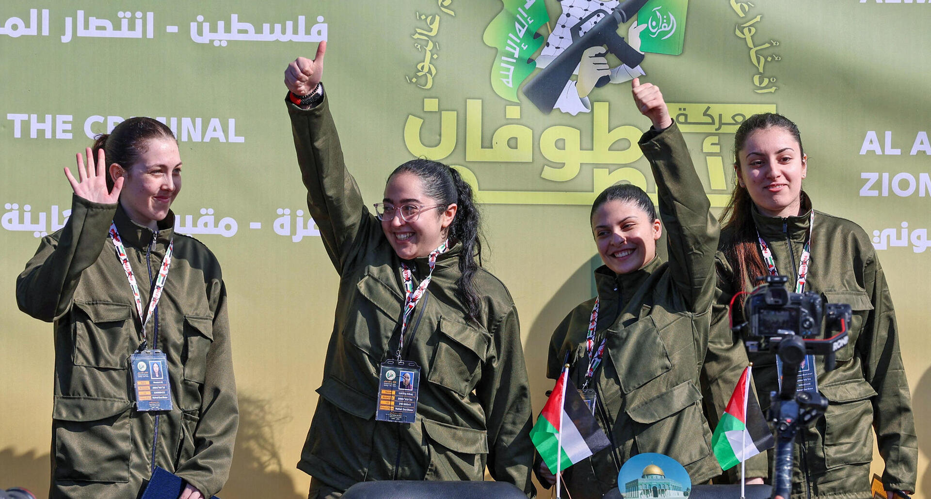 נעמה לוי לירי אלבג דניאלה גלבוע ו קרינה אריב מנופפים על במה לפני שלוחמי חמאס מוסרים אותם לצוות מהצלב האדום בעיר עזה ב-25 בינואר 2025