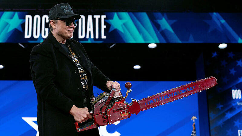 אלון מאסק בוועידה שנערכה במרילנד ארה"ב פברואר 2025 הביא עימו מסור כסמל לקיצוצים בממשל DOGE