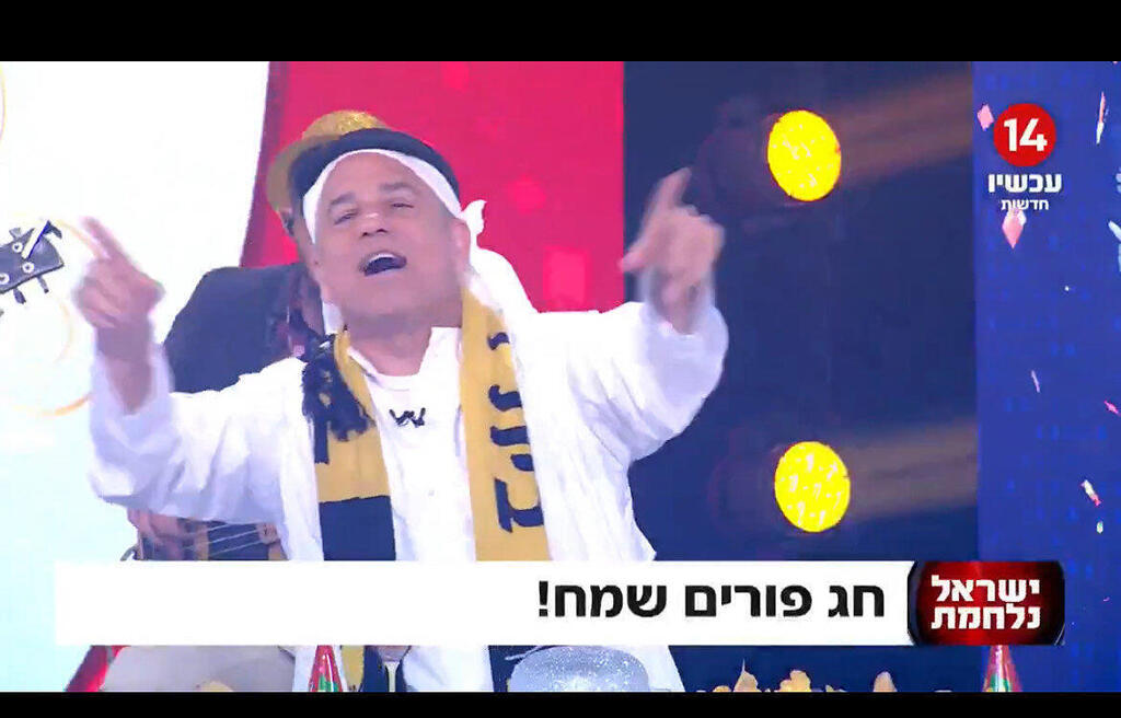 מתוך שידורי ערוץ 14. המטרה האמיתית: ביטול השידור הציבורי (גלי צה”ל וכאן), שליטה פוליטית, סנקציות וקנסות במטרה להרתיע מביקורת
(צילום: מסך) ינון מגל מגיש חדשות ערוץ 14 ב תחפושת של אוהד ביתר ירושלים ו ערבי