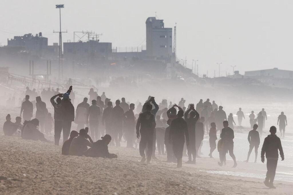 עזתים על החוף ברצועה, מחכים להטלת מטעני אספקה (צילום: Reuters) הקברניט מטוס תובלה סיוע הומניטרי
