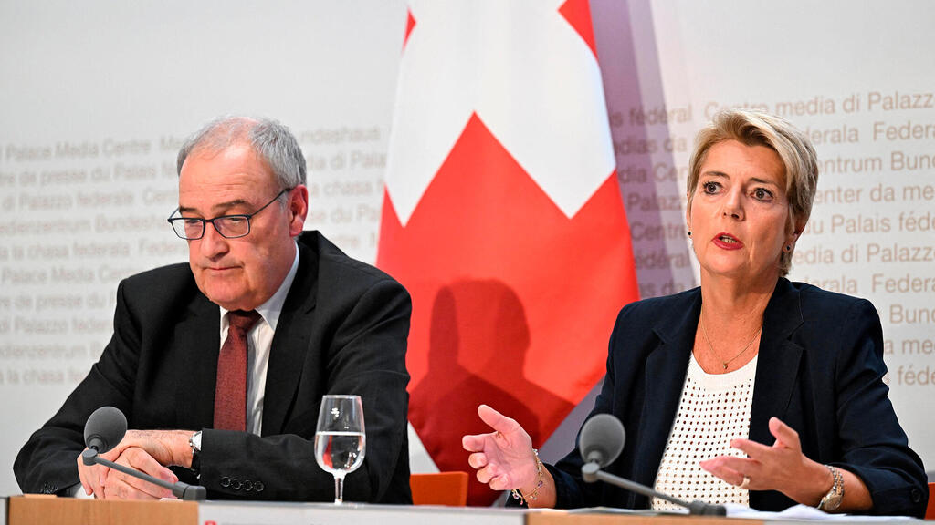 נשיאת שוויץ קארין קלר-סאטר נואמת לצד שר הכלכלה השוויצרי גיא פרמלין