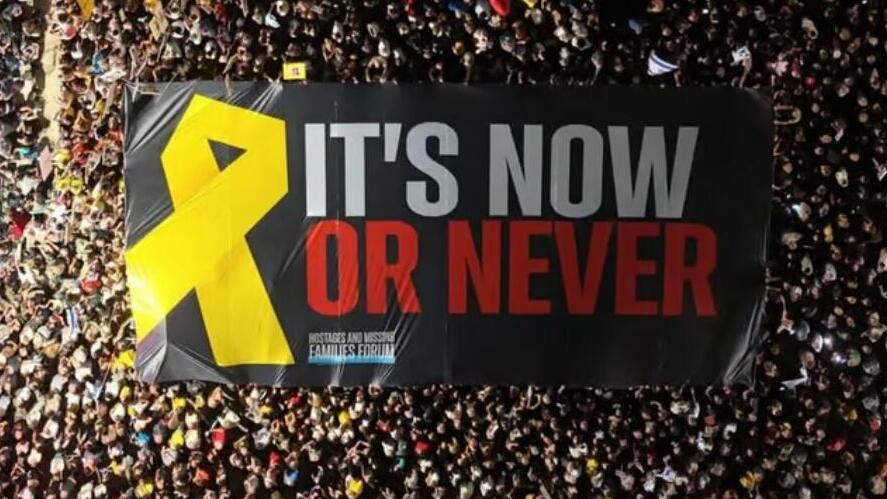 שלט ענק שנפרס בכיכר החטופים עם מסר באנגלית: "זה עכשיו או לעולם לא"