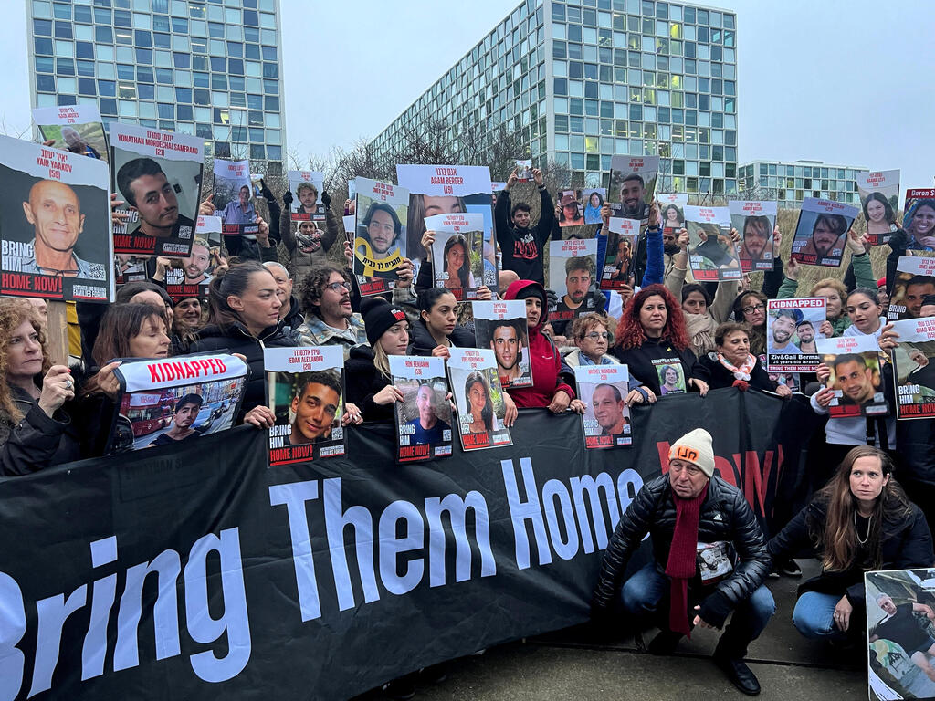 14 בפברואר 2024 | בני משפחות מפגינים מחוץ לבית הדין הבינלאומי בהאג. "חכרנו מטוס מאל על, כל המשלחת עלתה סביב 250 אלף דולר. זה המון כסף" (צילום: Rami Amichay/Reuters) בני משפחות מפגינים מחוץ לבית הדין הבינלאומי בהאג. "חכרנו מטוס מאל על, כל המשלחת עלתה סביב 250 אלף דולר. זה המון כסף"