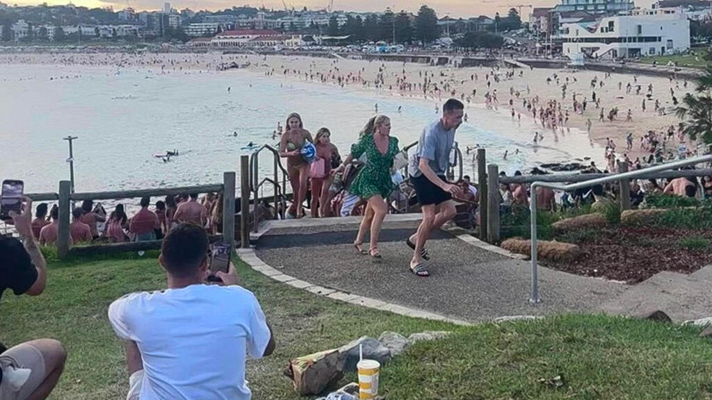 אנשים בורחים לאחר פיגוע הירי נגד הקהילה היהודית בחוף בונדי ביץ סידני אוסטרליה (צילום: MIKE ORTIZ/AFP) ננלטים מ פיגוע ירי נגד הקהילה היהודית בהדלקת נר חנוכה ראשון ב חוף בונדי ביץ סידני אוסטרליה