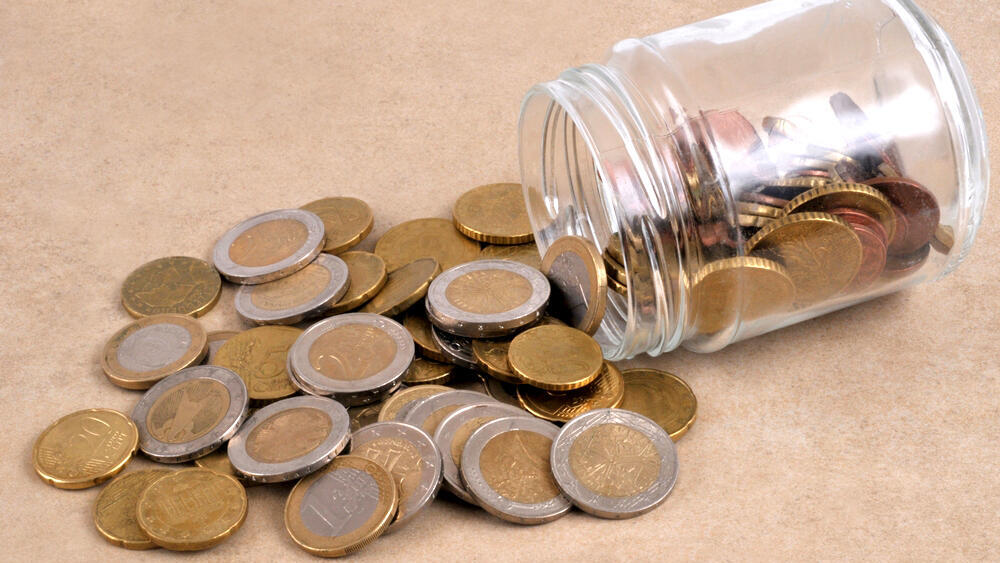 כסף מתוך צנצנת מטבעות חיסכון פנסיה