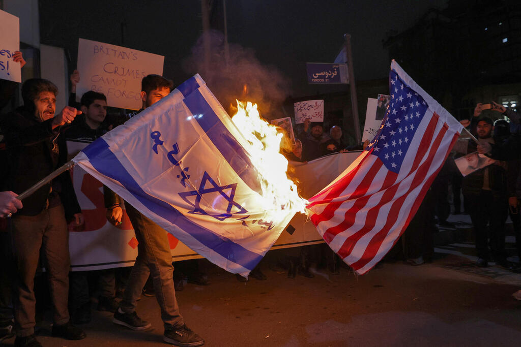 טהרן איראן אנשי מיליציה בסיג' הנאמנים למשטר שורפים דגלים של ישראל ו ארה"ב מול שגרירות בריטניה