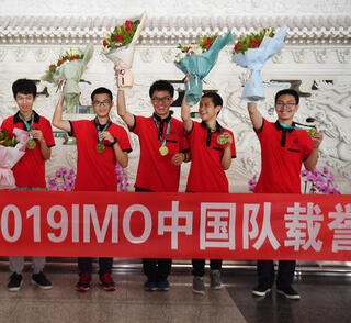  נבחרת סין לאולימפיאדת המתמטיקה ב־2019 מתקבלת בתשואות בשדה התעופה בבייג'ינג. בשנה שעברה 22 מתוך 23 נציגי המדינה לתחרויות המדעים חזרו עם מדליית זהב