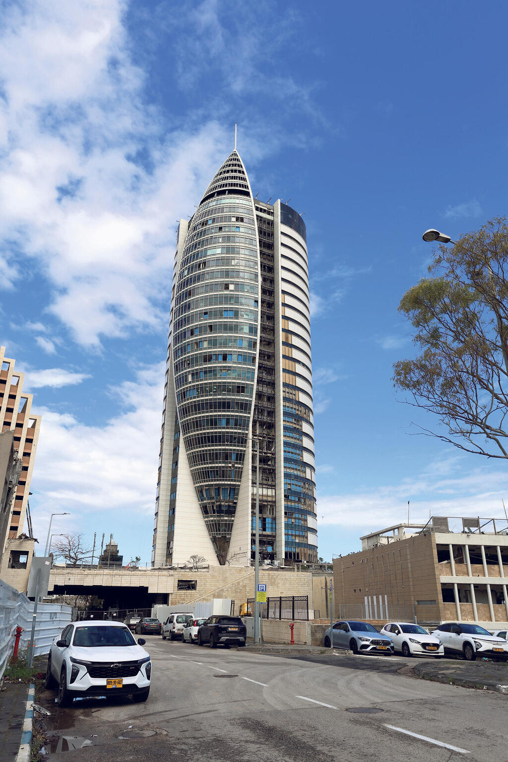 מגדל המפרש בן 29 הקומות בחיפה אכלס משרדי ממשלה שנאלצו להתפנות ממנו. מאז הפגיעה בו הוא מכונה בעיר "מגדל הטיל", ולא ברור מתי שיקומו יושלם
(צילום: אלעד גרשגורן) מוסף נדל"ן 2026 מגדל המפרש מגדל הטיל בניין קריית הממשלה חיפה