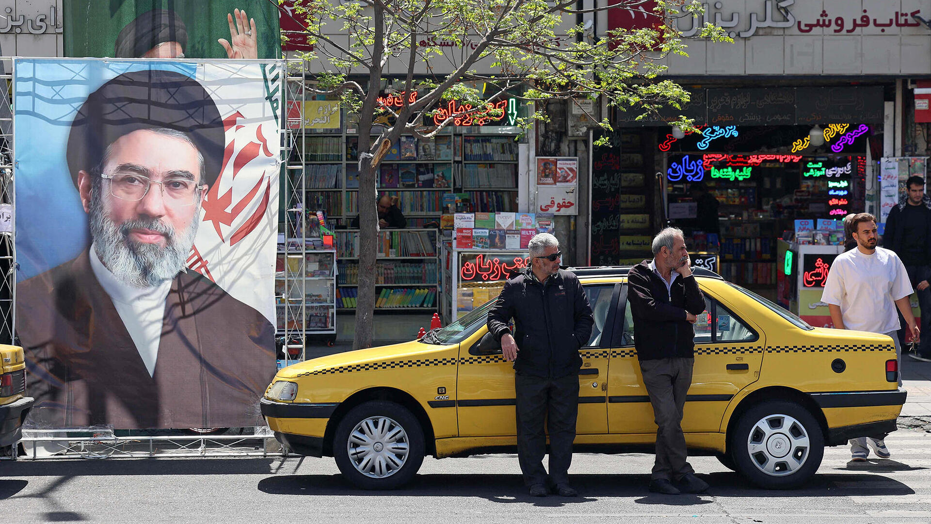 מונית בטהרן סמוך לתמונת המנהיג העליון מוג'תבא ח'אמנאי 5.4.26